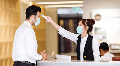 Woman at counter taking mans temperature