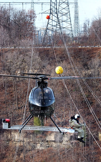 Power line marker being installed by helicopter