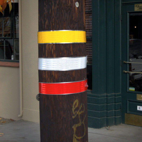 Yellow, white, and red BriteStripe shown wrapped around a wood power line pole.