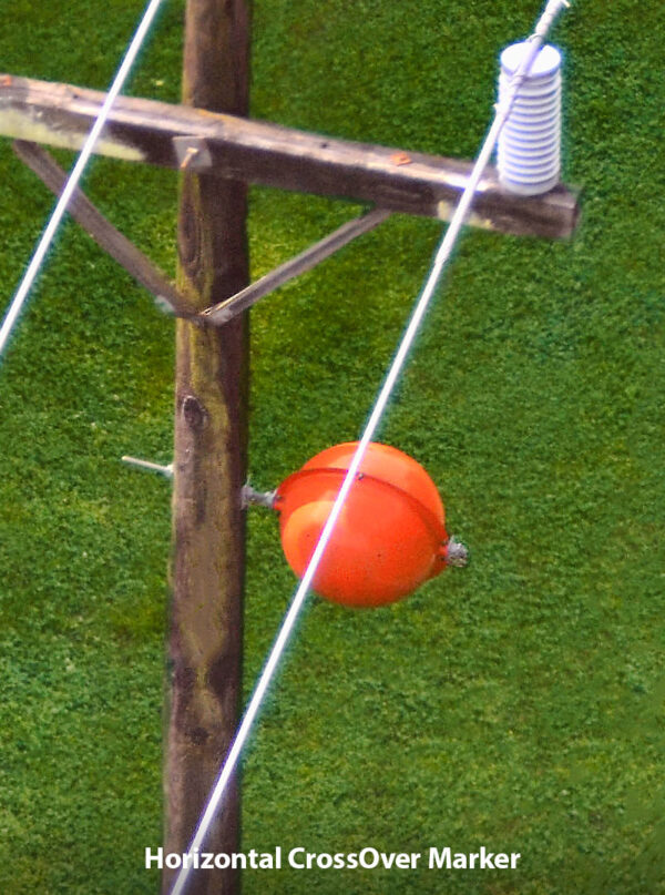 Horizontal crossover marker shown on the side of a power line pole.