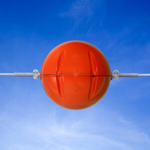 PRM-36 power line marker shown installed on a power line against a blue sky background.