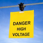 Yellow SpanMark flag hanging from a guy wire with the words, "Danger High Voltage" on it.