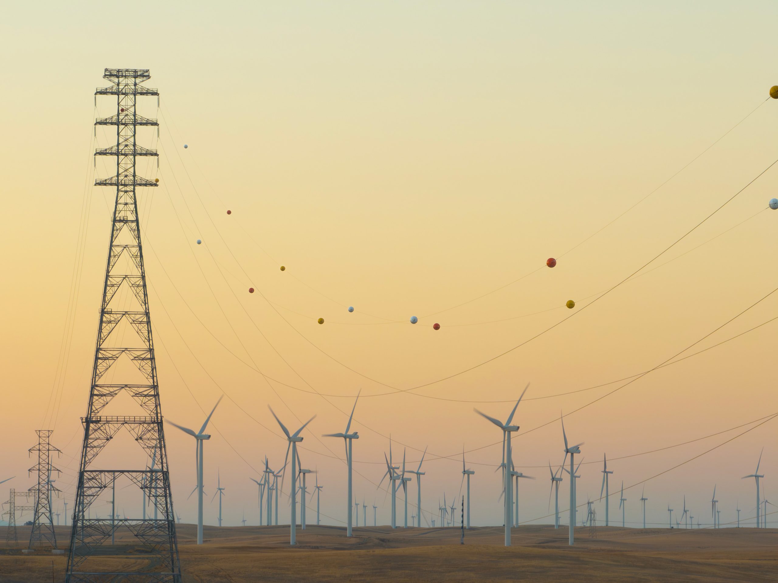 Orange power line marker ball shown in front of landscape full of wind turbines